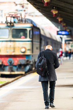 Tourist pulling luggage. Commuters walking at railroad station platform in Bucharest, Romania, 2022