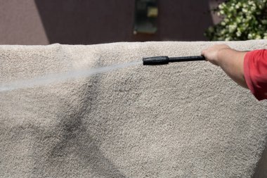 Yüksek basınçlı yıkamalı halılar. Yüksek basınçlı suyu yıkamak için halıyı silahla temizlemek.