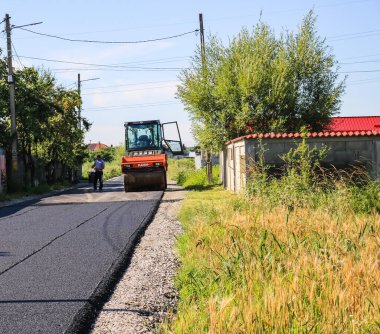 İşçiler ve asfaltlama makineleri. Romanya 'nın Bükreş kentinde inşaat ve yeni karayolunun asfaltlanması, 2022