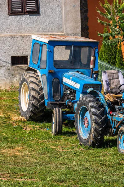 Old blue vintage tractor in fron of farm land in Viscri Village, Romania