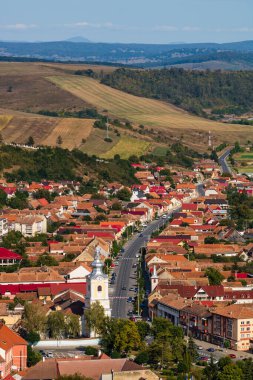 Rupea, Romanya 'daki tepeler, binalar, sokaklar, bitki örtüsü ve çevresiyle şehir merkezinin havadan görünüşü, 2021