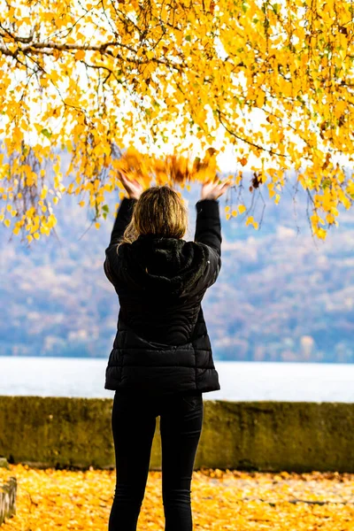 Autumn leaves fallen on alone woman walking on the autumn alley