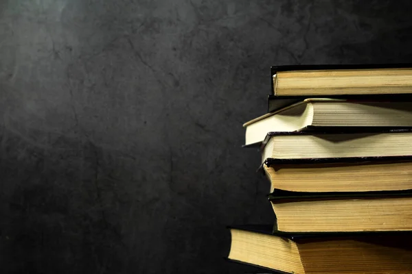 Eski kitaplar üst üste istiflenir, karanlık arka planda eski kitap koleksiyonu. Metin için yer alan kenar görünümü.