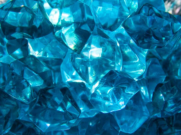 Bright blue crystals made of glass look like gems close-up in the blur. Background from blue stones crystals. Close-up.