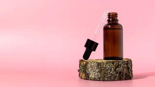 Бутылка коричневого стекла с капельницей на розовом фоне. Сыворотка или упаковка эфирного масла. Косметический макет продукта.. — стоковое фото