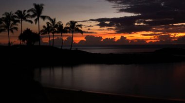 The last sliver of sunlight peaks through the clouds during sunset at Ko Olina Lagoons in the west coast of Oahu, Hawaii.