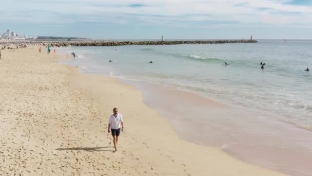 Человек идет вдоль песчаного берега в пределах Атлантического побережья — стоковое видео