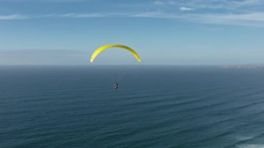 Deniz kıyısında uçan bir paraglider görüntüsü.