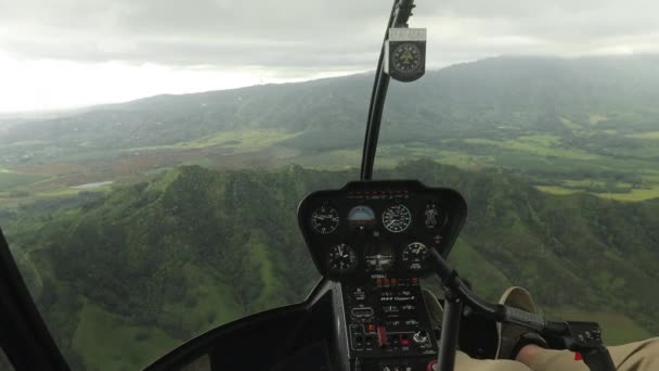 Вид на кокпіт з вертольота, що літає в дощовий день над зеленими вершинами гір Мауї. — стокове відео
