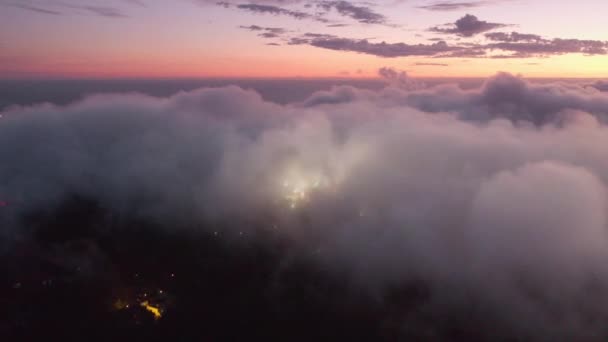 Nuvens brancas densas dentro do céu roxo e iluminando a cidade além — Vídeo de Stock