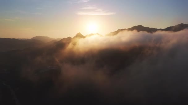 Terbang melalui awan cerah yang menakjubkan menuju matahari keemasan terbit di atas pegunungan — Stok Video