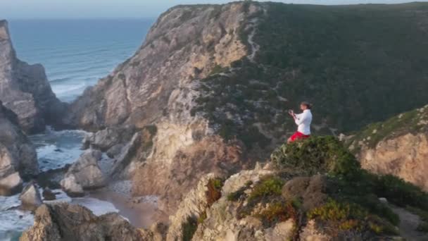 Een zonsondergang over een ongelooflijk steile kustlijn, gewassen door spetterende oceaangolven — Stockvideo
