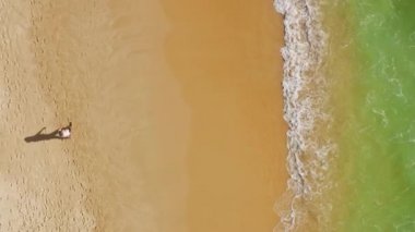 Kumlu sahilde köpüklü dalgalarla yıkanmış bir adamın robot görüntüsü.