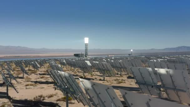 Удивительный вид солнечной башни на закат и панели стоят в ряд в полях — стоковое видео
