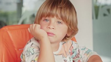 Güzel, uykucu bir çocuğun portresi, mutfakta kahvaltısını bekliyor.