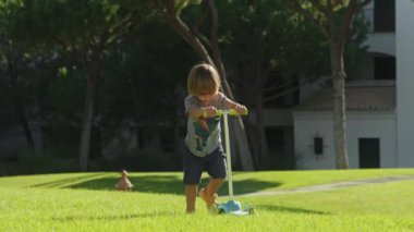 Lüks otel kompleksinde yeşil çimenleri ve uzun ağaçları olan beyaz bir çocuk.