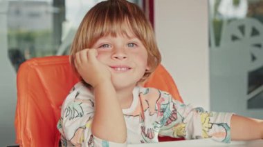 Mavi gözlü mutlu bir çocuğun yakın çekimi, güneşli bir hafta sonu sabahında eğleniyor.