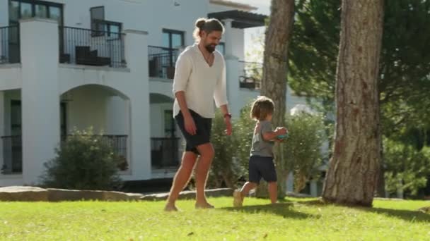 Pai brinca com seu filho no jardim em uma manhã ensolarada — Vídeo de Stock