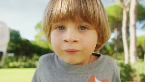 Retrato de un chico lindo con ojos azules jugando al aire libre — Vídeos de Stock