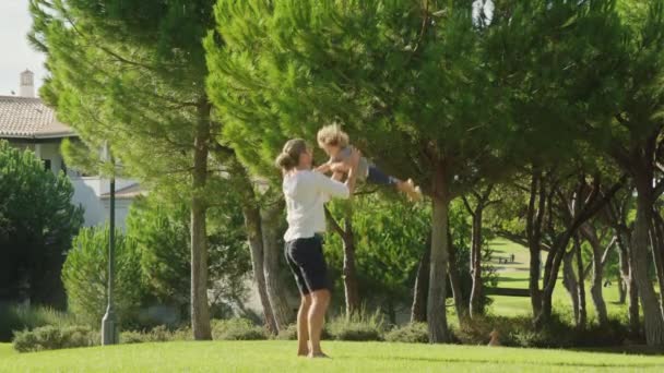 Mały chłopiec bawi się z ojcem na bujnej trawie na świeżym powietrzu — Wideo stockowe
