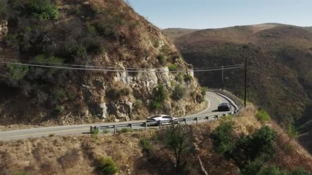 Повітря з двох екзотичних спортивних автомобілів, що їдуть гірською дорогою в каньйоні Малібу (США). — стокове відео