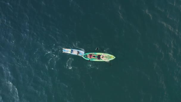 Overhead aerial view of people in colorful kayak towing surfer on paddle board — Stock Video