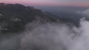 Pembe gün batımı gökyüzü ile mor bulutlar arasında uçuyor.