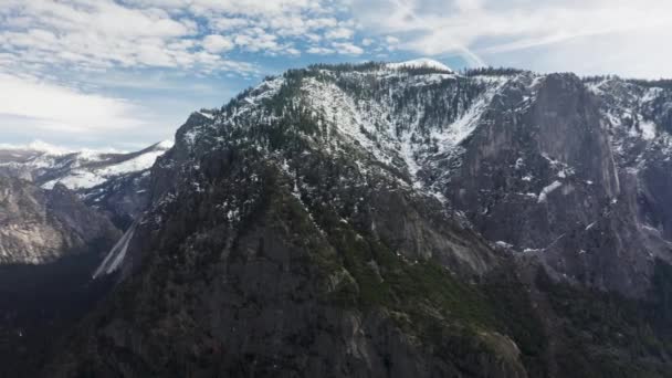 Vista aérea de las rocas, cubiertas por un denso bosque verde con cielo azul detrás — Vídeos de Stock