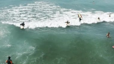 Sörf tahtasında dalga yakalayan insanların insansız hava aracı görüntüleri.