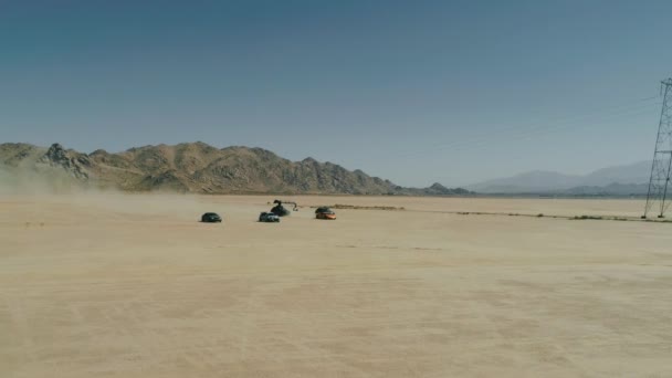 Vue aérienne du processus de tournage, des cicatrices sportives conduisant par des voitures exotiques passant dans le désert — Video