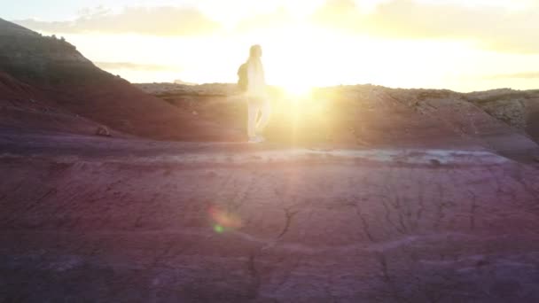 Gelukkig vrouw wandelen in kleurrijke rode woestijn bij gouden zonsondergang met zonnestralen flare — Stockvideo