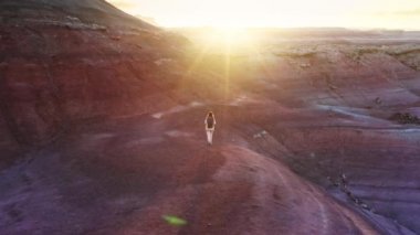 Genç maceraperest kadın pembe mor çöl dağ tepesinin yanından geçiyor, Utah USA 4K