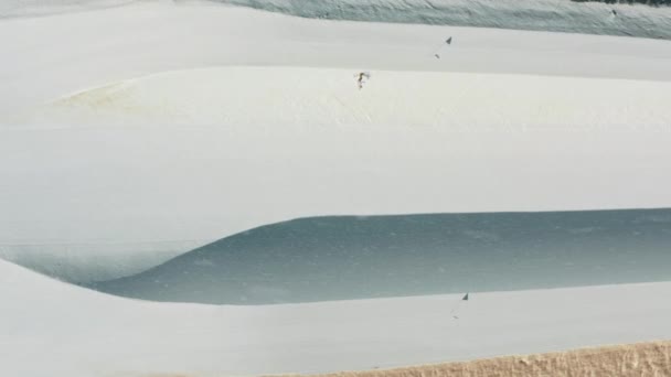 스노보드의 절반 파이프에 떨어지는 부드러운 눈, 산비탈 위로 점프하는 자유 선수 — 비디오