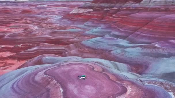 Zwei glückliche Reisende liegen auf einem farbenfrohen Hügel in der filmischen bunten Wüste — Stockvideo