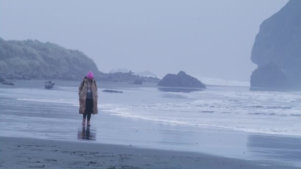 Powolny ruch Czerwony aparat ujęcie samotnie atrakcyjnej kobiety spacery Oregon płaszcz plaży — Wideo stockowe