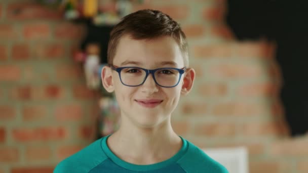 Retrato de um menino sorridente em óculos e camiseta verde — Vídeo de Stock