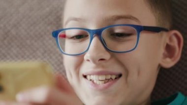 Akıllı telefonunu kapalı mekanda kullanırken internetten iletişim kuran beyaz tatlı bir genç.