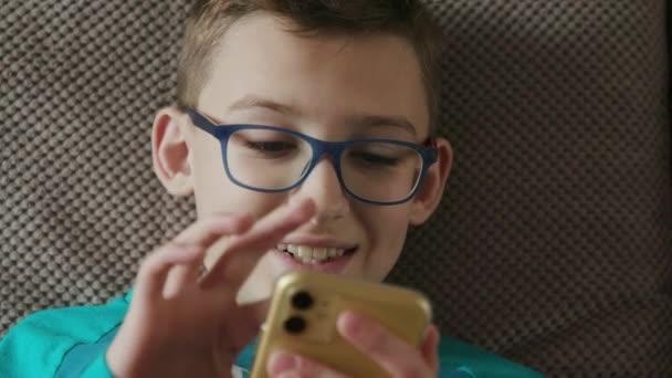 Gros plan d'un adolescent, utilisant un téléphone pour jouer à l'intérieur — Video