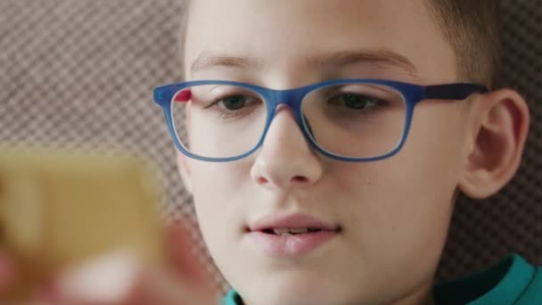 Caucasian schoolboy, wearing glasses, surfing wireless internet indoors — Stock Video