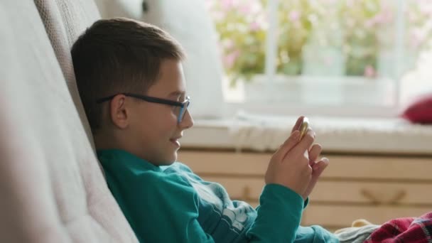 Вид сбоку школьника, играющего в онлайн-игры с помощью смартфона — стоковое видео