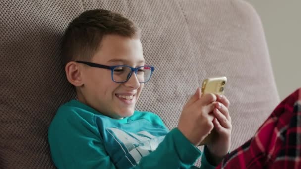 Nahaufnahme eines kaukasischen Kindes, das auf einer Couch liegt und es genießt, online zu spielen — Stockvideo