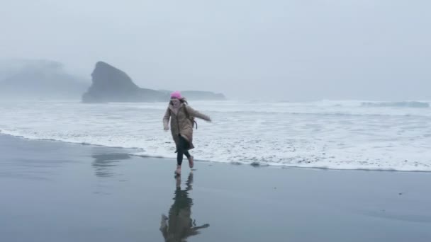 Воздушный выстрел красивая смеющаяся женщина бежит от океанских волн США, зима 4K — стоковое видео