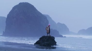 Kayalık kayalıklardaki turist yağmurlu bir günde arka planda, yavaş çekimde mutlu yolculuklar.