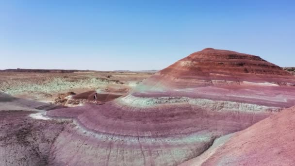 Voyageur féminin avec sac à dos sur une surface désertique peinte vibrante, aérienne pittoresque — Video