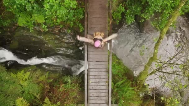 Alegre feliz alegre joven turista en puente de madera mojada bailando bajo la lluvia — Vídeos de Stock