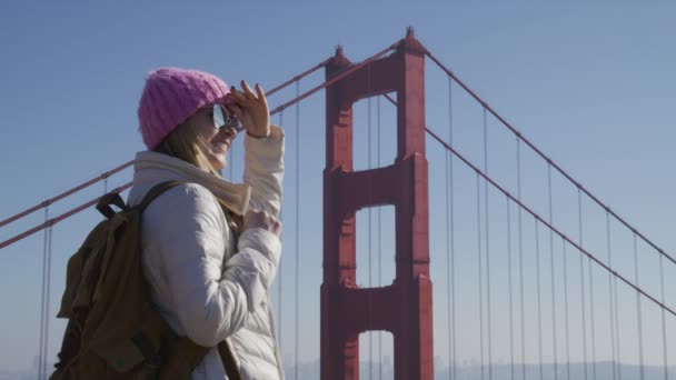 Porträt einer glücklichen Hipster-Frau, die an einem sonnigen Tag auf die Golden Gate Bridge blickt — Stockvideo