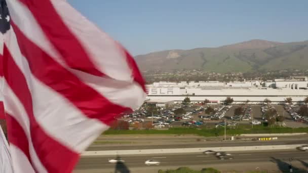 Concepto de cero emisiones. Bandera de EE.UU. ondeando por el viento en la fábrica de vehículos Tesla Electric — Vídeo de stock