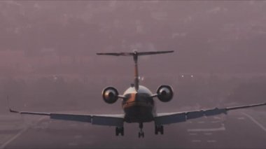 Büyük yolcu uçağı aşağıdan görüldüğü gibi bir havaalanı pistine doğru uçuyor.