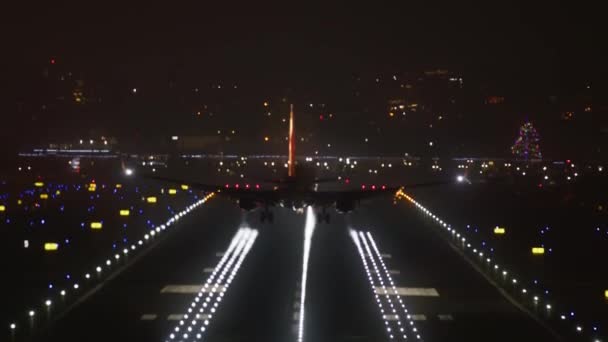 Μεγάλο επιβατικό αεροπλάνο προσγειώνεται τη νύχτα με ένα αστικό τοπίο στο παρασκήνιο — Αρχείο Βίντεο