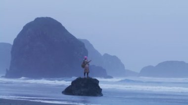 Macera için akıllı telefon kamerasını kullanan bir kadın, turistler manzaralı kayalık plajların tadını çıkarıyorlar.